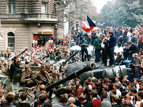 Czech youths holding a Czechoslovak flag stand on an overturned truck as other citizens surround Soviet tanks in Prague on Aug. 21, 1968 as the Soviet-led invasion by Warsaw Pact armies crushed the so-called Prague Spring reform in former Czechoslovakia.