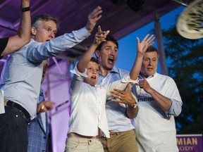 Prime Minister Justin Trudeau helps son Xavier, centre, to throw a plate alongside Toronto Mayor John Tory to mark the first day of the Taste of the Danforth street festival in Toronto, on Friday, August 10, 2018.