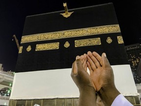 A Muslim pilgrim, only hands seen, prays near the Kaaba, the cubic building at the Grand Mosque, ahead of the annual Hajj pilgrimage, in the Muslim holy city of Mecca, Saudi Arabia, Friday, Aug. 17, 2018. The annual Islamic pilgrimage draws millions of visitors each year, making it the largest yearly gathering of people in the world.