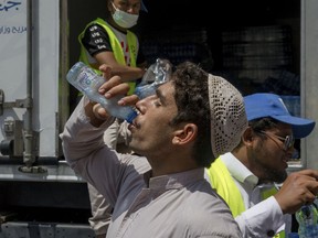 A Muslim pilgrim drinks water distributed by Saudi volunteers near the Grand Mosque, ahead of the annual Hajj pilgrimage, in the Muslim holy city of Mecca, Saudi Arabia, Muslim holy city of Mecca, Saudi Arabia, Saturday, Aug. 18, 2018. The annual Islamic pilgrimage draws millions of visitors each year, making it the largest yearly gathering of people in the world.