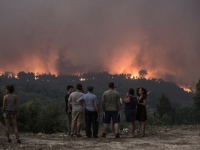 People observe as fire gets closer to the village of Monchique, in southern Portugal's Algarve region, Sunday, Aug. 5 2018. Over 700 firefighters were still battling a forest fire near the Portuguese town of Monchique in the southern Algarve region, a popular tourist destination.