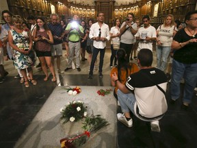 People stand around the tomb of former Spanish dictator Francisco Franco inside the basilica at the the Valley of the Fallen monument near El Escorial, outside Madrid on Friday, Aug. 24, 2018. Spain's center-left government has approved legal amendments that it says will ensure the remains of former dictator Gen. Francisco Franco can soon be dug up and removed from a controversial mausoleum.