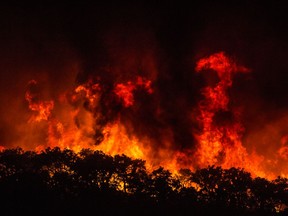 Large flames are seen on a hillside outside the village of Monchique, in southern Portugal's Algarve region, Sunday, Aug. 5 2018. Over 700 firefighters were still battling a forest fire near the Portuguese town of Monchique in the southern Algarve region, a popular tourist destination.