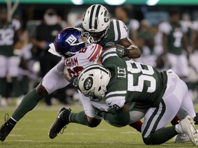 New York Jets linebacker Avery Williamson, top, and linebacker Darron Lee (58) tackle New York Giants tight end Evan Engram (88) who fumbled the ball on the play during the second quarter of an NFL football game, Friday, Aug. 24, 2018, in East Rutherford, N.J.