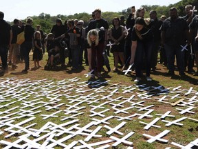 In this photo taken Oct. 30, 2017 people place white crosses, representing farmers killed in the country, at a ceremony at the Vorrtrekker Monument in Pretoria, South Africa.  U.S. President Donald Trump has tweeted that he has asked the Secretary of State Mike Pompeo to "closely study the South African land and farm seizures and expropriations and the large scale killing of farmers." Trump added, "South African Government is now seizing land from white farmers."