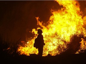 A firefighter keeps watch as the Holy Fire burns in the Cleveland National Forest along a hillside at Temescal Valley in Corona, Calif., Thursday, Aug. 9, 2018. Firefighters fought a desperate battle to stop the Holy Fire from reaching homes as the blaze surged through the Cleveland National Forest above the city of Lake Elsinore and its surrounding communities.