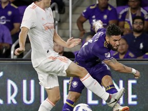 Orlando City's Dom Dwyer, right, takes a shot on goal past Atlanta United's Michael Parkhurst during the first half of an MLS soccer match, Friday, Aug. 24, 2018, in Orlando, Fla.