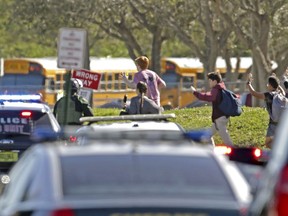 FILE - In this Feb. 14, 2018 file photo, students run with their hands in the air following a shooting at Marjory Stoneman Douglas High School in Parkland, Fla. Florida authorities released video showing the chaos and heroism that took place outside a building during the high school massacre. The Broward Sheriff's Office released videos Wednesday, Aug. 22 from five cameras surrounding the building at Marjory Stoneman Douglas High School where 17 died Feb. 14. The silent videos show blurred images of students running from the building.