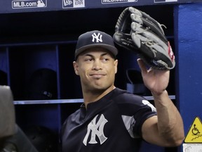 New York Yankees left fielder Giancarlo Stanton waves as he walks into the dugout before a baseball game against the Miami Marlins, Tuesday, Aug. 21, 2018, in Miami. Stanton says it's weird to return to Miami, where he played his first eight major league season and will now try to help the Yankees beat the Marlins.