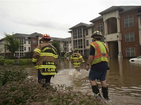 Members of the Campbell County Fire Department wade through water at an apartment complex Thursday, Aug. 2, 2018 in Lynchburg, Va. The National Weather Service said up to six inches of rain fell within hours, filling College Lake near Lynchburg beyond capacity. The service says a failure of the College Lake Dam could flood parts of Lynchburg with 17 feet of water in just seven minutes.