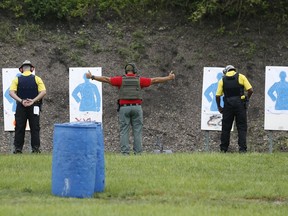 In this Monday, July 30, 2018 photo, a Broward Sheriff's Office (BSO) trainer, center, signals at the ready as he is flanked by two Broward County Public Schools newly-hired armed guardians during firearms training at BSO's gun range at Markham Park in Sunrise, Fla. Twenty-two of the Florida school districts are supplementing officers with "guardians" - armed civilians or staff. They are vetted, receive 132 hours of training and must attain a higher score on the state firearms test than rookie police officers.