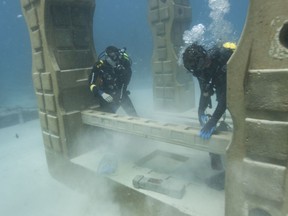 In this July 19, 2018 photo, Jim Hutslar, right, operations director for Neptune Memorial Reef, and Ray Lowenstein, left, prepare to install a memorial plaque for Buel and Linda Payne, affixed to at cement baluster mixed with their ashes, at the Neptune Memorial Reef near Miami Beach, Fla.