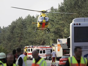 A helicopter hovers over the Autobahn A 19 in Linstow near Rostock, northern Germany, Friday, Aug. 17, 2018, after a bus was driven into a ditch and turned over. Six people were seriously injured and a further 10 slightly hurt.