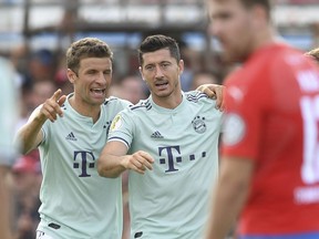 Bayern's Robert Lewandowski celebrates with his teammate Thomas Mueller, left, after scoring the opening goal during the German Soccer Cup, DFB-Pokal, match between fourth league club SV Drochtersen/Assel and Bayern Munich in Drochtersen, northern Germany, Saturday, Aug. 18, 2018.