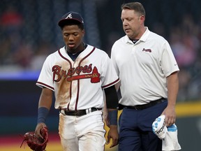 Atlanta Braves' Ronald Acuna Jr. leaves the field with a training staff member in the second inning of a baseball game after being hit by a pitch from Miami Marlins starting pitcher Jose Urena in the first inning Wednesday, Aug. 15, 2018, in Atlanta.