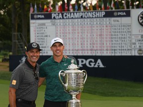 Brooks Koepka of the United States poses with Claude Harmon and the Wanamaker Trophy on the 18th green after winning the 2018 PGA Championship with a score of -16 at Bellerive Country Club on August 12, 2018 in St Louis, Missouri.