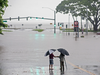 People stand near flood waters from Hurricane Lane making the intersection of Kamehameha Avenue and Pauahi Street impassable, Aug. 23, 2018, in Hilo, Hawaii.