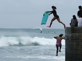 Bodyboarders jump into the surf along Waikiki Beach ahead of Hurricane Lane, Friday, Aug. 24, 2018, in Honolulu.