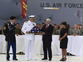 Vice President Mike Pence, second from right, receives a flag from Navy Rear Adm. Jon Kreitz, deputy director of the POW/MIA Accounting Agency, second from left, during a visit to Joint Base Pearl Harbor-Hickam in Hawaii, Wednesday, Aug. 1, 2018. The flag presented was draped over one of the transfer cases with remains believed to be of American service members who fell in the Korean War. The remains were returned to the United States Wednesday. North Korea handed over the remains last week. Karen Pence, right, and Sgt. Maj. Michael Swam, left, watch.