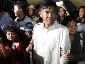 A former Radio Free Asia reporter Uon Chhin, foreground, is held his hand by his wife, second from right, outside the main prison of Prey Sar at the outskirt of Phnom Penh, Cambodia, Tuesday, Aug. 21, 2018. Two Cambodian journalists who had worked for U.S.-funded Radio Free Asia and are charged with espionage have been released on bail, a day after a pardon freed four land rights activists from prison.