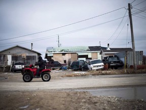 A man rides his ATV in the northern Ontario First Nations reserve in Attawapiskat, Ont., on Tuesday, April 19, 2016. The Trudeau Liberals are offering Indigenous communities $30 million in prize money as part of a contest that could end up rewriting the rules about how the federal government funds badly needed housing on-reserve.