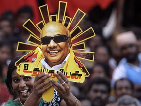 FILE- In this April 22, 2014 file photo, a supporter holds up a cutout with a portrait of Dravida Munnetra Kazhagam (DMK) party chief Muthuvel Karunanidhi during an election rally in Chennai, India. Karunanidhi, a scriptwriter-turned-politician in the southern Indian state of Tamil Nadu, has died after a prolonged illness. He was 94.