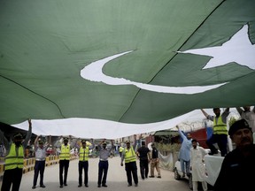 Pakistani police officers hold a national flag during a rally to mark the country's Independence Day, in Peshawar, Pakistan, Tuesday, Aug 14, 2018. The anniversary comes amid political change with a new government taking over this week following the July 25 general elections. Pakistan gained independence when British left India and split the subcontinent in 1947.