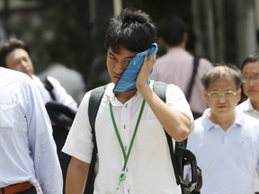 A man wipes the sweat from his face in the scorching heat at a business district in Tokyo, Monday, July 23, 2018.