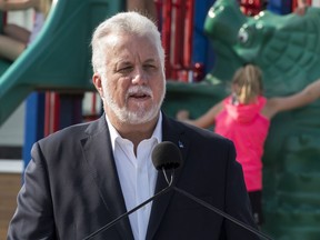 Primary school students play behind Quebec Liberal Leader Philippe Couillard as he speaks at a news conference to announce his education program for youth and families, in St-Felicien, Que., Monday, August 27, 2018.