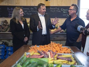 Coalition Avenir Quebec Leader Francois Legault, centre, speaks to owner Ivanhoe Brochu, right, while visiting a fruit and vegetable producer, Thursday, August 30, 2018 in Saint-Henri Que. Local candidate Stephanie Lachance, left, looks on.