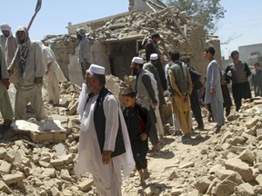 Afghan men stand near a damaged house following a Taliban attack in Ghazni, Afghanistan, Wednesday, Aug. 15, 2018. A Taliban assault on two adjacent checkpoints in northern Afghanistan killed at least 30 soldiers and police, officials said Wednesday. Life gradually returned to normal in parts of the eastern city of Ghazni after a massive insurgent attack last week, with sporadic gunbattles still underway in some neighborhoods.