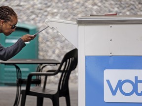 FILE - In this Tuesday, Aug. 2, 2018, file photo Eudora Carter inserts her ballot into a drop-off voting box in Seattle. Washington voters will decide which candidates advance to the November ballot in 10 congressional races, a U.S. Senate seat and dozens of legislative contests in the state's primary election.