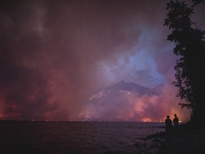 FILE - This Sunday, Aug. 12, 2018 file photo provided by the National Park Service shows the Howe Ridge Fire from across Lake McDonald in Glacier National Park, Mont. The wildfire in northwest Montana's Glacier National Park is forcing evacuations and has burned within a mile of the scenic Going-to-the-Sun Road. The Missoulian reported Sunday, Aug. 19, 2018 that the Howe Ridge fire had grown to more than 12 square miles, and shifting winds are forecast over the next day and a half. (National Park Service via AP, File)