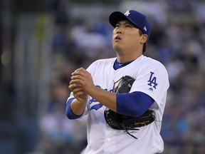 Los Angeles Dodgers starting pitcher Hyun-Jin Ryu rubs up the ball before pitching during the first inning of the team's baseball game against the San Francisco Giants on Wednesday, Aug. 15, 2018, in Los Angeles.