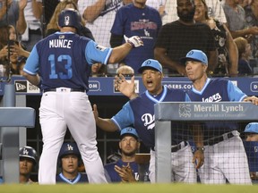 Los Angeles Dodgers' Max Muncy (13) is greeted at the dugout by manager Dave Roberts after hitting a home run during the seventh inning of a baseball game against the San Diego Padres, Saturday, Aug. 25, 2018, in Los Angeles.