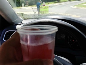 This Saturday, Aug. 4 2018, photo provided by James Castellano, of Monroe, N.C., shows a drink he bought from a boy, background, in Monroe. A teenager who held up the North Carolina lemonade stand for $17 was still at large Monday, Aug. 6, and authorities said they hoped to track him through surveillance footage and possible DNA and fingerprint tests.