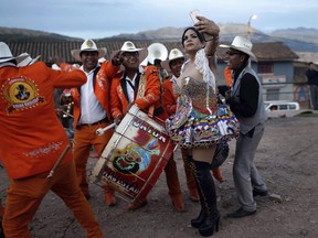 In this Sunday, Aug. 5, 2018 photo, transgender Carolina, dressed as a "china", poses for a photo with Majestic Union band members during celebrations honoring Our Lady of Copacabana, in Cuzco, Peru. Despite the persistent discrimination suffered by members of the LGBT community in the country, Carolina says she and her friends are invited every year to take part in the religious celebration. "I never feel discrimination," said Carolina, "and sometimes I receive a little money for my dancing."