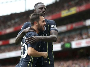 Manchester City's Bernardo Silva, left, celebrates with Benjamin Mendy after scoring his side's second goal of the game  during the English Premier League soccer match between Arsenal and Manchester united at the Emirates Stadium, London. Sunday Aug. 12, 2018.