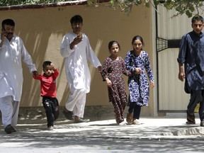 Families leave their houses during a nearby clash between insurgents and security forces in Kabul, Afghanistan, Thursday, Aug. 16, 2018. Gunmen besieged a compound belonging to the Afghan intelligence service in Kabul on Thursday, police said, as the city's Shiite residents held funeral services for the victims of a horrific suicide bombing the previous day that left over 30 dead.