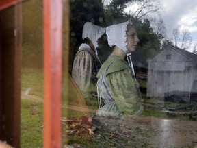 In this Wednesday, Aug. 22, 2018, photo, Loralei Arndt, right, sits behind a farm house window as she reenacts an 1830s farm worker at Old Sturbridge Village, in Sturbridge, Mass. With a $75,000 grant from the National Endowment for the Humanities, Old Sturbridge Village, a living history museum that depicts life in a small New England town in the 1830s, is taking a deep look at the way it presents the past, including the roles of minorities and women, in an effort to stay relevant to a 21st century audience.