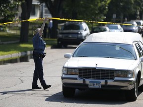 St. Paul Police officer Colleen Lesedil lifs crime scene tape, as the Ramsey county medical examiner leaves the scene with the body of a person that was shot and killed by St. Paul police in the 900 block of St. Anthony Avenue Sunday, Aug. 5, 2018, in St. Paul, Minn. Police say officers shot an armed man while responding to a 911 call early Sunday about shots fired at a home.