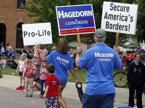 In this June 10, 2018 photo, volunteers for Minnesota 1st District congressional candidate Jim Hagedorn carry signs during a parade in Waterville, Minn. Waterville's 54th annual Bullhead Days parade included Republican Hagedorn and Democrat Dan Feehan, candidates who came to shake as many hands as they could in the open seat race which promises to be one of the most closely watched races in the country.