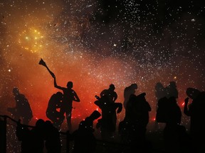 In this July 30, 2018 photo, revelers play in and around a huge burning papier mache bull full of exploding fireworks, in the Santiago Teyuhalco neighborhood of Tultepec, Mexico. Last year there were 40 fireworks accidents in the State of Mexico, where Tultepec is located, that claimed 24 lives and injured more than 100, according to the governmental Mexican Institute of Pyrotechnics; through July 5 of this year, there have been 16 accidents with 40 dead and more than 70 hurt.