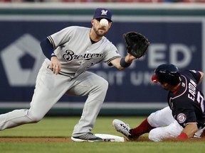 Milwaukee Brewers second baseman Travis Shaw, left, cannot make the tag on Washington Nationals' Adam Eaton who steals second during the first inning of a baseball game at Nationals Park, Friday, Aug. 31, 2018, in Washington.