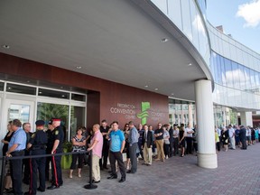 Mourners line up to enter the Fredericton Convention Centre, where a public visitation for Fredericton police constables Sara Burns and Robb Costello is being held, in Fredericton on Thursday, Aug. 16, 2018.