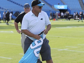 Carolina Panthers owner David Tepper carries Julius Peppers jersey as he walks to mid-field before a preseason NFL football game against the Miami Dolphins in Charlotte, N.C., Friday, Aug. 17, 2018.