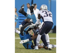 Carolina Panthers' Cam Newton, left, lands on his head and shoulders after being hit by New England Patriots' Deatrich Wise, center, as Devin McCourty (32) watches during the first half of a preseason NFL football game in Charlotte, N.C., Friday, Aug. 24, 2018.