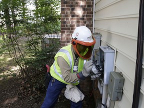 In this photo taken Friday, July 13, 2018 Grid One Solutions employee Spencer Powell removes an older electric meter to install a new smart meter for Duke Energy Progress at a residence in Raleigh, N.C.  Electric utilities are pouring billions of dollars into a race to prevent terrorists or enemy governments from shutting down the power grid while also making the delivery system ready for a world with much more renewable energy. Utilities have long based their business on building power plants and selling the juice to customers to pay for it all. With energy conservation making big new plants less necessary, utilities are banking on future profits from updating the power grid.