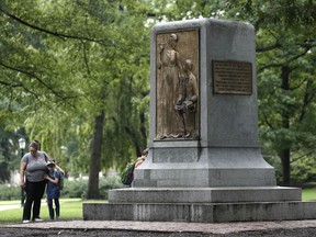 People gather near the remaining monument following a Monday night rally where the Confederate statue known as Silent Sam was toppled from it's pedestal by protesters at the University of North Carolina in Chapel Hill, N.C., Tuesday, Aug. 21, 2018.  The bronze figure of a Southern soldier atop a tall stone pedestal was erected by the United Daughters of the Confederacy in 1913.