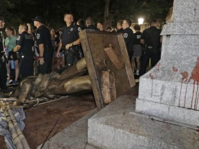 Police stand guard after the confederate statue known as Silent Sam was toppled by protesters on campus at the University of North Carolina in Chapel Hill, N.C., Monday, Aug. 20, 2018.